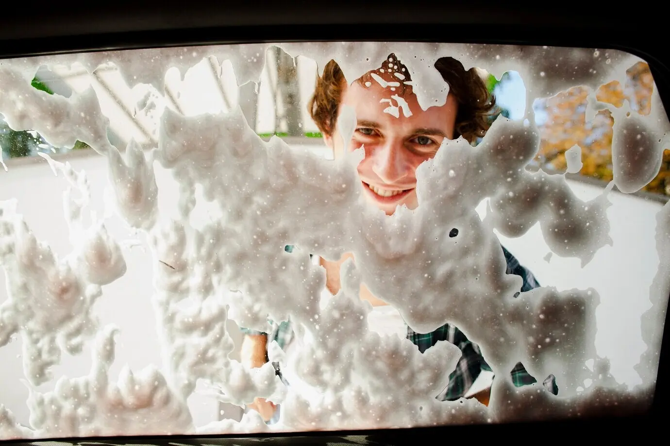 Close-up of a man washing a rear window.