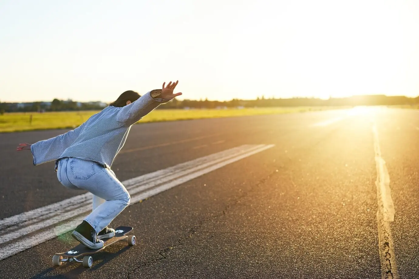 A happy skater girl, a smiling woman, riding her skateboard and having fun on an empty street, enjoying a cruise.