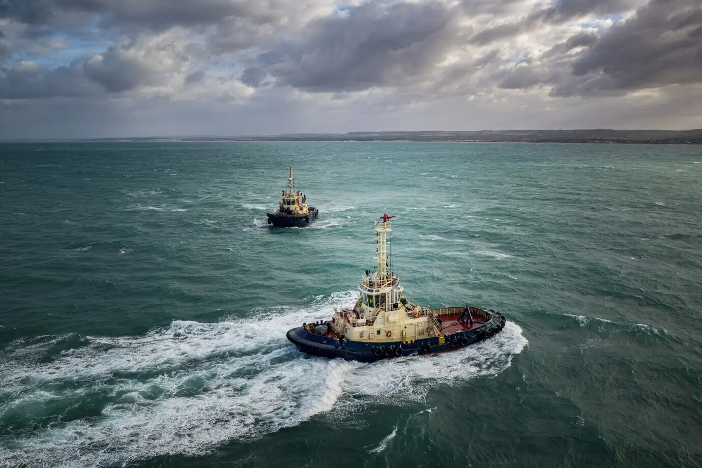Investigative boats navigate a turquoise ocean beneath a cloudy sky.